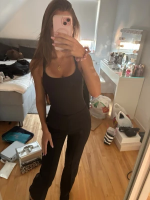 Svarta utsvängda kostymbyxor  - Säljer ett par svarta leggings med bootcut-modell och hög midja. De är tighta upptill och har utsvängda ben, vilket ger en snygg siluett. Materialet är stretchigt och bekvämt, perfekt för dig som gillar stilrena och enkla byxor.