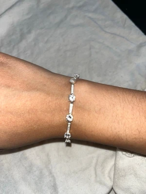 Silver armband - Snyggt armband i silverfärg med glittrande pärlor och små detaljer. Armbandet har en tunn kedja och flera runda pärlor som ger en elegant look. Perfekt accessoar för att lyfta din outfit.