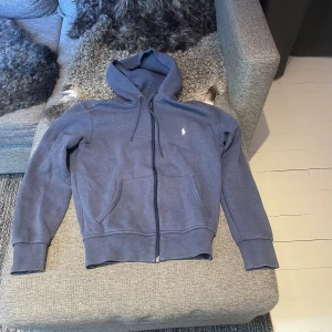 Ralph Lauren Hoodie - Blå Ralph Lauren Zip-up hoodie i storlek XS. Ett mångsidigt plagg som passar till nästan hela garderoben! Använd men är i bra skick och fri från defekter. 