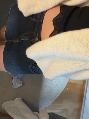 Mörkblå jeanskjol  - Säljer en mörkblå jeanskjol med rå, fransad kant nertill och klassiska fickor fram. Kjolen har knapp och dragkedja i midjan och är i en kort modell. Perfekt för dig som gillar en enkel men snygg denimlook.