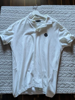 Moncler White Polo Shirt - Klassisk vit pikétröja från Moncler med ikoniskt tygmärke på bröstet och fin passform.
