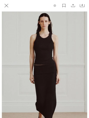 Svart långkjol i ribbad bomull - Stilren svart långkjol i ribbad bomull med tight passform. Kjolen har en enkel och minimalistisk design som passar perfekt till olika looks. Supersnygg att matcha med ett linne eller crop top.
