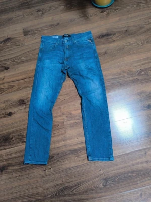 Blå jeans från Replay w32  - Säljer ett par klassiska blå jeans från Replay med  fem fickor. Jeansen har snygga kontrastsömmar, samt Replay-logga på myntfickan. Perfekta till en avslappnad stil och tillverkade i mjuk denim.