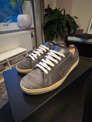 Blå Saint Laurent skor - Säljer mina blå SL06 Low Tops. De har tecken på användning och har tappat lite färg på mockan. Lite fläckar på högra skon. Storlek 40.5 men passar mer 41. Innersulan är 26,3 cm. Limmat lite vid toeboxen. Pris kan diskuteras! 