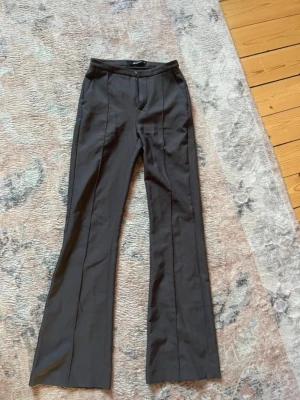 grå kostymbyxor  - Snygga grå kostymbyxor från Gina Tricot i storlek XS. Byxorna har pressveck framtill, hög midja och lätt utsvängda ben. Tillverkade i ett mjukt och följsamt material som ger en clean look.