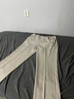 Beiga vida linnebyxor med resårmidja - Snygga och luftiga linnebyxor i beige med rak, vid passform och resår i midjan för extra komfort. Perfekta för en avslappnad och stilren look. Materialet känns lätt och svalt, vilket gör dem grymma till sommaren.