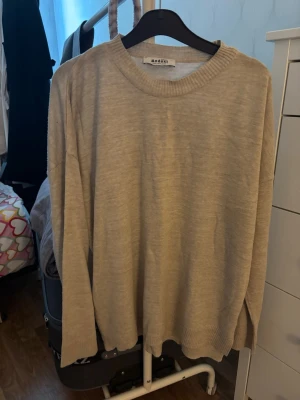 Beige stickad tröja från Mouli - En enkel och stilren beige stickad tröja från Mouli. Tröjan har rund halsringning, långa ärmar och ribbade muddar vid ärmslut och nederkant. Perfekt basplagg för lager på lager och passar till det mesta. Köpte den i Turkiet företaget heter defacto