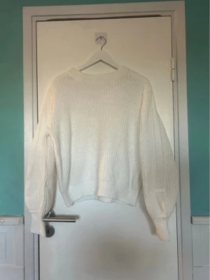 Stickad tröja - Säljer en vit oversized stickad tröja med breda ärmar och ribbade muddar. Tröjan har en avslappnad passform och rund halsringning. Perfekt för lager på lager och en chill look. Använd en gång
