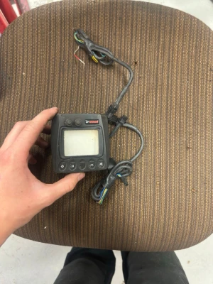Digital kontrollpanel för fordon med kablar - En svart digital kontrollpanel med display och flera knappar, samt två anslutna kablar med färgade ledare. Panelen har fyrkantig form och är tillverkad i plast. Perfekt för dig som behöver styra eller övervaka elektronik i fordon eller maskiner.