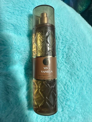 Viva Vanilla parfym mist 236 ml bath&body works - Viva Vanilla parfym mist i en elegant, transparent plastflaska med rutmönster och bronsfärgad etikett. Flaskan har en guldig spraypump och rymmer 236 ml. Doften har tydliga inslag av vanilj och ger en varm, söt känsla.helt ny