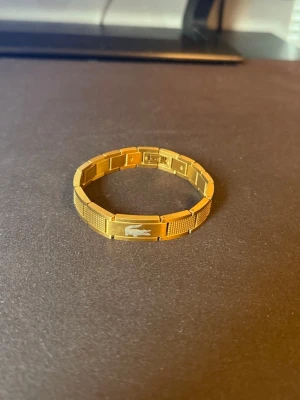 Lacoste armband - GULD lacoste armband i storlek 20cm. (Kan förkorta hemma till 18cm utan problem) SKICK 10/10
