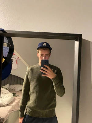 Olivgrön tröja jlindeberg - En enkel och stilren olivgrön stickad tröja från Jlindeberg. Perfekt för lager på lager och funkar till både jeans och mjukisbyxor. Materialet mjukt och bekvämt. 