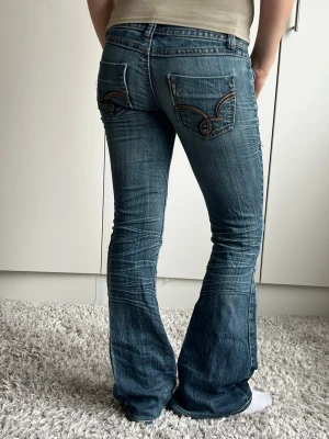 Blå bootcut jeans med broderade fickor - Midjemått 33cm rakt över, 77cm innerbenslängd ❣️
