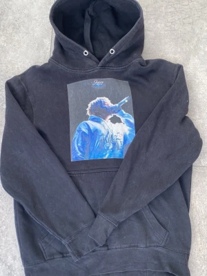 Svart hoodie med Juice WRLD-tryck - Svart hoodie med stor huva och magficka. På bröstet finns ett färgstarkt tryck av Juice WRLD.Perfekt r streetwear. Hör av er vid frågor✅