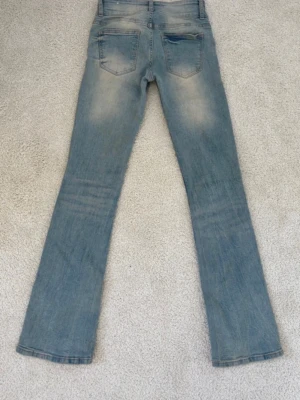 Ljusblå low waist bootcut jeans  - Säljer ett par ljusblå low waist bootcut jeans från Bershka i storlek 34. Jeansen har en dubbelknäppning framtill och är i mycket bra skick.