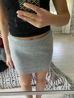 Ljusgrå stickad kjol - Superfin ljusgrå stickad kortkjol med ribbade kanter i midjan och nederkant. Enkel och stilren design som är lätt att matcha med olika toppar. Aldrig använd. 