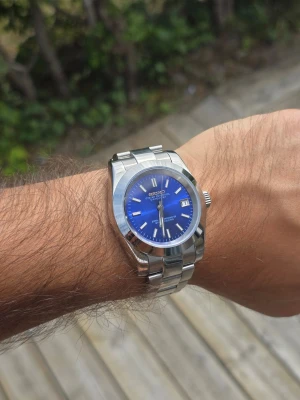 Blå Seiko Datejust Mod 39mm - Helt ny Seiko Datejust mod med en riktigt snygg blå urtavla som skiftar fint i ljuset 🔵✨ Boetten är 39 mm och ger en väldigt bra passform på handleden ⌚️ Stilren design med silverfärgad boett och länk i rostfritt stål. Datumvisning vid klockan 3 och en klassisk look som passar både till vardags och finare tillfällen ✅ Den blå urtavlan tillsammans med det polerade stålet gör att klockan verkligen sticker ut 🔥 Custombyggd Seiko mod och alltså inte en fabriksoriginal Seiko-modell. Skickas välpackad 