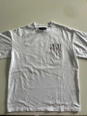 Vit AMIRI t-shirt - Säljer en vit t-shirt från AMIRI med tryck på bröstet och ryggen där loggan droppar ner. Oversized passform