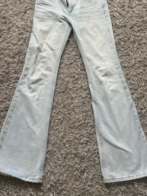 Ljusblå utsvängda jeans från Crocker - Säljer ett par ljusblå jeans från Crocker med utsvängda ben och klassisk femficksmodell. Jeansen är tillverkade i ett mjukt denimtyg. Perfekta för dig som gillar retrostil och vill ha ett par riktigt snygga jeans med 70-talsvibbar. Midjemåttet är ca 35cm. Finns jätte små fläckar men som knappt syns 