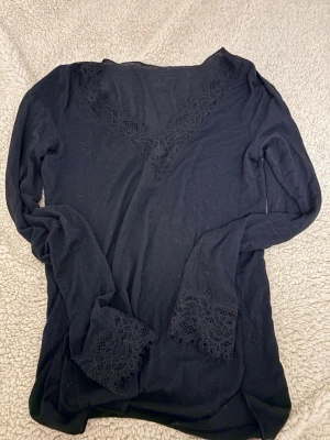 Svart intimismi tröja - Mysig svart långärmad loungewear från Intimissimi med v-ringning och fina spetsdetaljer vid halsringning och ärmslut. Perfekt för avslappnade dagar hemma när du vill känna dig både bekväm och snygg.