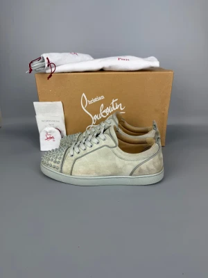 Christian Louboutin Louis Junior Spikes Sneaker Grey | 41 - Välanvända sneakers i gott skick. Grå, storlek 41. Originalbox, dammpåse, extra snören och tillbehör ingår.