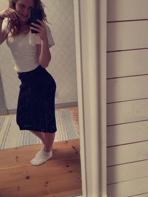 Svart långkjol i enkel design - En svart långkjol med rak passform och midjehög resår. Kjolen är stilren och passar perfekt till en enkel topp eller stickad tröja. Materialet är stickat, mjukt och följsamt. Tillverkat i polyester, viskos och nylon. 💕Nypris 399 kronor.