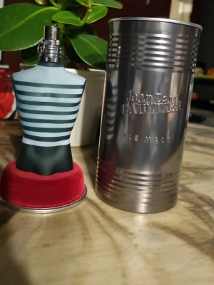 Jean Paul Gaultier Le Male parfym - Ikonisk parfymflaska formad som en manlig torso i blått och turkost med vita ränder. Kommer med original metallburk med präglad logga. Flaskan har en unik design som sticker ut på hyllan och är perfekt för dig som gillar klassiska dofter med modern twist vilkent menade en doft som är mjuk och fräsch. Typ 110ml kvar använd typ 7 gånger 