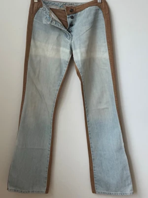 Tvåfärgade jeans från Biscote - Helt Unika jeans från Biscote med ljusblå front och bruna sidor i läder samt midja. Köpta för 1800 och knappt använda därav priset ❤️