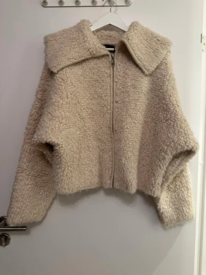 Beige teddyjacka med dragkedja - Supermjuk teddyjacka i beige med stor krage och dragkedja framtill. Jackan är oversized passform storlek m och är aldrig använd.