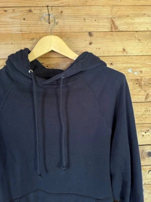 JEANERICA Hood U001 navy hoodie XL - JEANERICA Hood U001 hoodie i navy, strl XL. Minimalistisk modell i 100% ekologisk bomull med raglanärmar, känguruficka och dragsko i huvan. Mjuk sweatshirtkvalitet med lätt naturlig blekning och avslappnad passform. Fint begagnat skick.