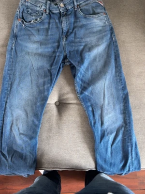Blå raka jeans med fem fickor - Säljer ett par klassiska blå jeans med rak passform och fem fickor. Jeansen har en snygg tvättad look och är tillverkade i denim. Perfekta för dig som gillar en enkel och tidlös stil.