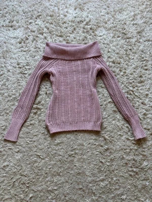Ljusrosa off shoulder stickad tröja - Supersnygg ljusrosa stickad tröja från KappAhl med off shoulder-krage och ribbade muddar. Tröjan har lång ärm och är gjord i mjukt material som passar perfekt till kalla dagar. Enkel att styla med jeans eller kjol för en trendig look.