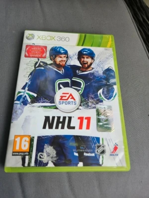 NHL 11 till Xbox 360 - NHL 11 till Xbox 360 är ett ishockeyspel från EA Sports. Omslaget har gröna och vita färger med två hockeyspelare i blå matchtröjor. Spelet har PEGI 16-märkning och erbjuder realistisk hockeyaction med flera spellägen.