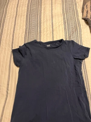 Mörkblå t-shirt från 157 - En basic mörkblå t-shirt från 157 med rund hals och korta ärmar. Tillverkad i mjuk bomull med lite elastan för extra stretch och bekväm passform. Perfekt till jeans eller shorts för en enkel och clean look.