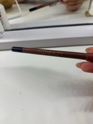 Huda Beauty Lip Contour 2.0 Terracotta - Läppenna från Huda Beauty i nyansen Terracotta. Pennan har en varm brun-orange ton och är i klassisk pennform med svart spets och brun hylsa. Perfekt för att definiera och forma läpparna med ett naturligt resultat.