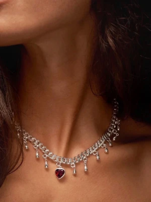 Maria Nilsdotter SÖKER!! - Snyggt silverfärgat halsband med droppformade hängen och ett rött hjärta i mitten. Kedjan är grov och ger ett trendigt intryck. Perfekt accessoar för att lyfta din outfit med en cool detalj.