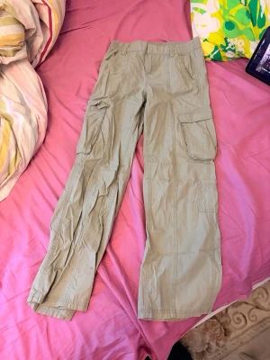 Beiga cargobyxor med fickor - Snygga beiga cargobyxor med raka ben och flera praktiska fickor på sidorna. Byxorna har hög midja och klassisk cargostil, perfekta för en avslappnad och trendig look. Tillverkade i ett lätt och bekvämt material som passar året runt.