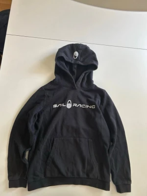 sail racing hoodie - supersnygg svart sail racing hoodie,säljer då den inte kommer till användning.använd cirka 3 gånger,storlek 160 men sitter som en XS🤍