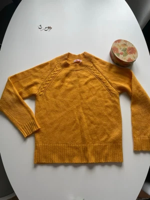  stickad tröja -  Tröjan har ribbstickade muddar vid ärmslut och nederkant samt en högre rund halsringning. Perfekt för dig som gillar färg och vill ha något bekvämt och snyggt.