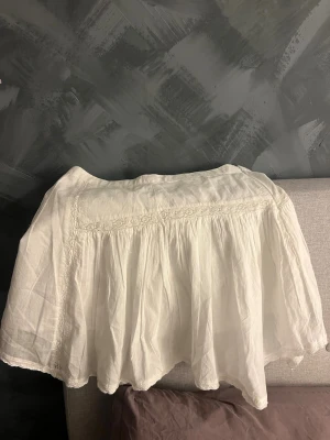 Vit kortkjol med spets från Bik Bok - Söt vit kortkjol från Bik Bok i bomull med fina spetsdetaljer och volang. Kjolen har en luftig och flowy passform som ger en avslappnad och trendig look. Perfekt att matcha med en crop top eller stickad tröja.