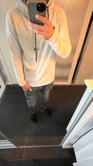 Jack and Jones hoodie - Säljer en grå  j&j hoodie med huva och mörkblå snören, samt en dekorativ träknapp. Tröjan har en praktisk ficka framtill med en liten Originals-lapp. Materialet är mjukt och ribbat, perfekt för en avslappnad stil.