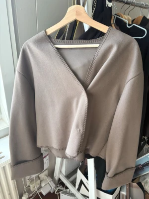 Gina tricot tunn jacka - Säljer en fin tunn jacka från Gina Tricot i storlek S. Jackan är i en stilren taupe/beigegrå färg och har en enkel, oversize-inspirerad modell med fina detaljer längs kanterna. Perfekt som en lättare jacka under vår, sommar och tidig höst. 🤎 Jackan är använd men har fortfarande mycket kvar att ge. Det finns några mindre märken/fläckar, vilket syns på bilderna, samt ett mindre hål i tyget. Därför säljs den billigare och skicket är tydligt visat i bilderna. Pris kan diskuteras vid snabb köp!