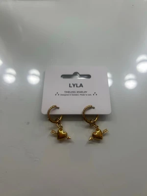 Guldörhängen med hjärthänge från LYLA - Snygga örhängen i guldfärg från LYLA, säljs då jag har dubletter de är aldrig använda och därför i helt nytt skick, allt guld är kvar (säljer även ringen på sista bilderna) mycke lägre pris en ordinarie 