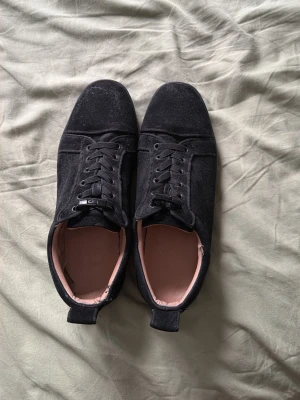 Svarta sneakers i mocka - Säljer ett par stilrena svarta sneakers i mocka med klassisk snörning och låg profil. Skorna har en mjuk, ljusrosa insida och diskreta sömmar för en clean look. Perfekta för dig som gillar minimalistisk stil och vill ha något som funkar till det mesta.