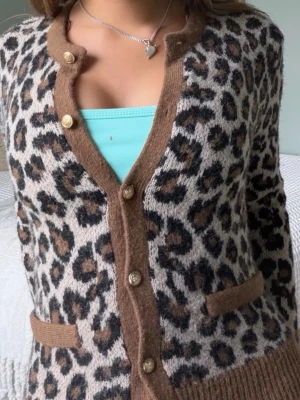 Leopardmönstrad kofta från Zara  - Snygg leopardmönstrad kofta med bruna ribbade kanter och guldknappar. Koftan har två fickor framtill och är stickad i ett mjukt material. 