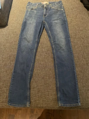 Levi's 511 Slim jeans blå - Säljer ett par klassiska blå Levi's 511 Slim jeans med smal passform. Jeansen har fem fickor, dragkedjegylf och snygga kontrastsömmar. Perfekta för dig som gillar en modern och stilren look.
