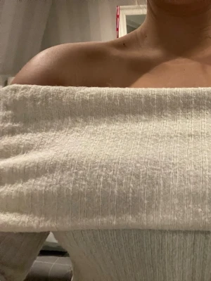 Off shoulder stickad tröja cremevit - Trendig off shoulder stickad tröja i cremevitt med ribbad struktur. Långa ärmar och bred urringning som sitter snyggt över axlarna. Perfekt för dig som vill ha en stilren och mysig look.