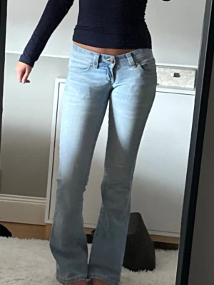 Ljusblå bootcut jeans - Säljer ett par ljusblå bootcut jeans med klassisk femficksdesign och normal midja. Jeansen har en lätt utsvängd passform nedtill och är tillverkade i mjukt denimtyg. Perfekta för en avslappnad och trendig look. Jeansen är från a brand modell super low tall