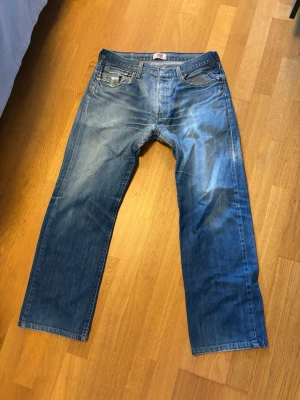 Blå raka jeans med slitningar - Säljer ett par riktigt schyssta jeans ifrån Levis. Storleken är 32 på både längden och i midjan 