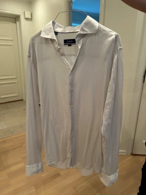 Vit skjorta från Eton, slim fit L - Klassisk vit skjorta från Eton i storlek L med slim fit. Skjortan har långa ärmar, knappar framtill och en stilren krage. Perfekt för dig som gillar en clean och tidlös look. Tillverkad i mjukt bomullstyg.